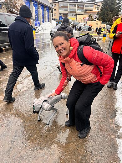 Mikaela pats a robot dog at WEF